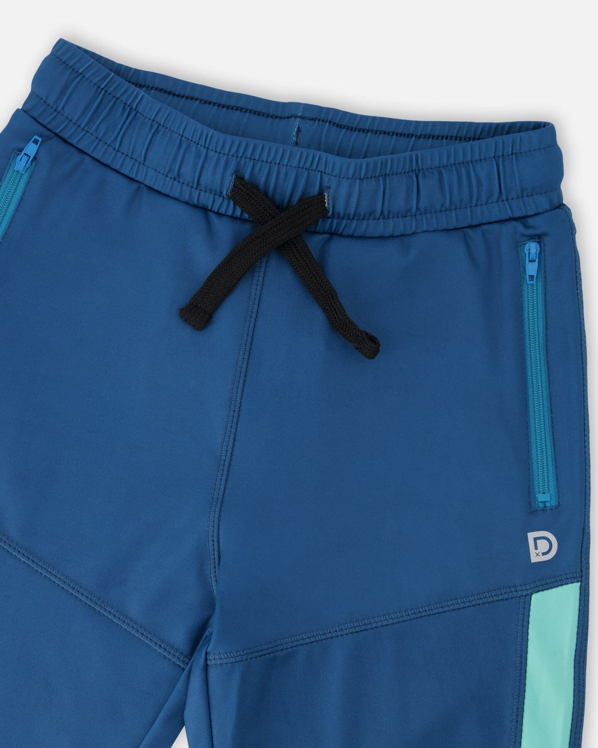 Close-up of the drawstring waist and zippered pocket on the teal pants