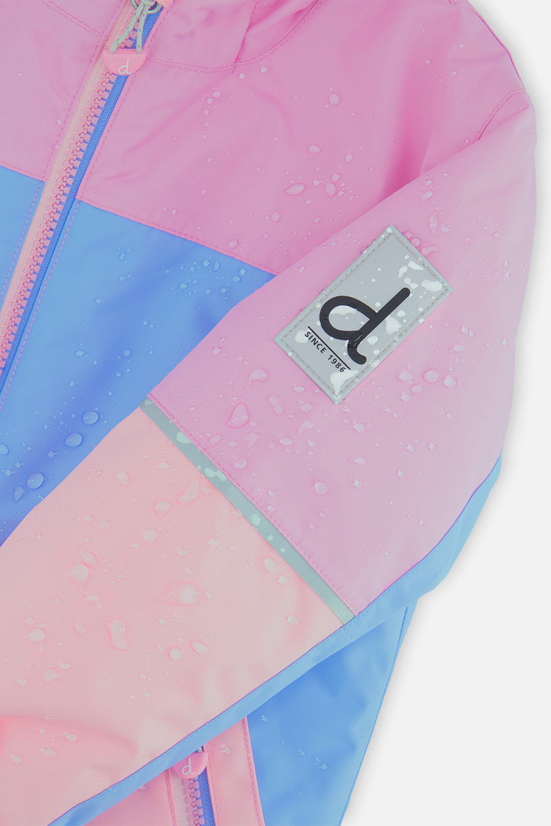 Close-up of the pink and blue CHILL jacket sleeve logo patch with water beading on the fabric