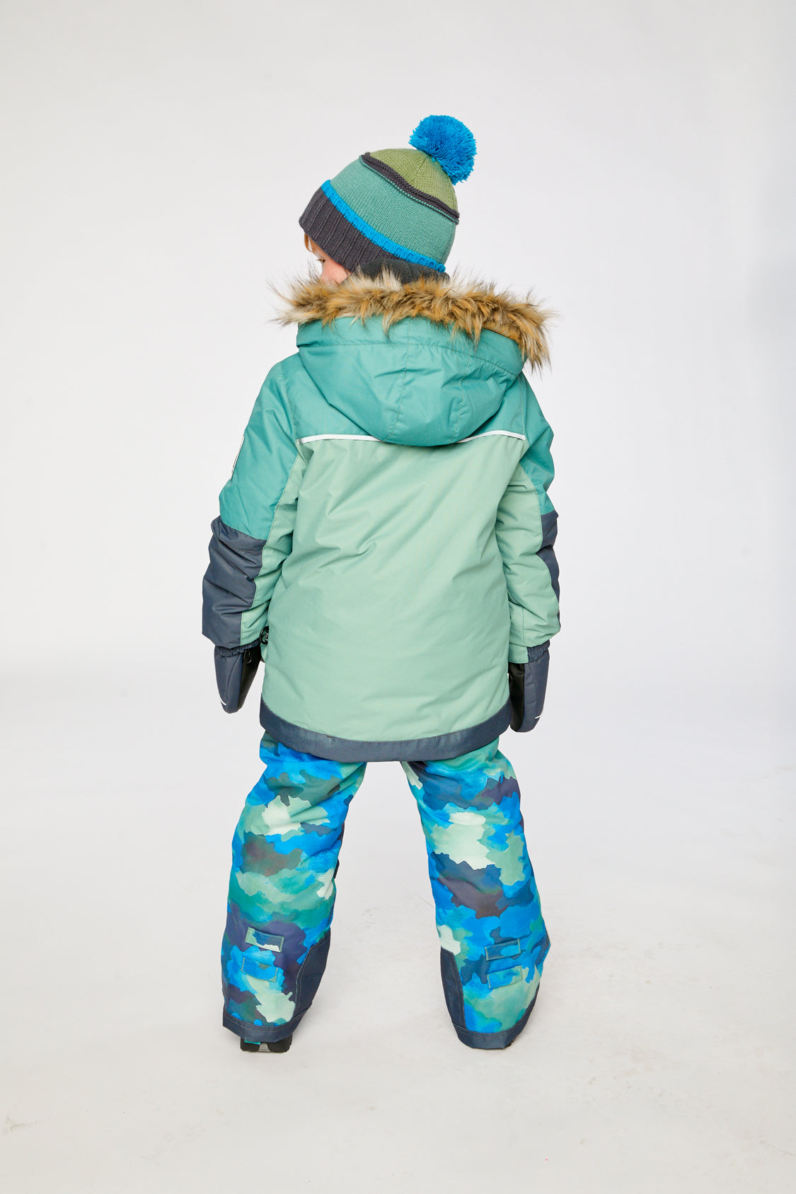 Child wearing the green and navy Deux par Deux PLAY snowsuit with blue camo pants, lookbook view 3