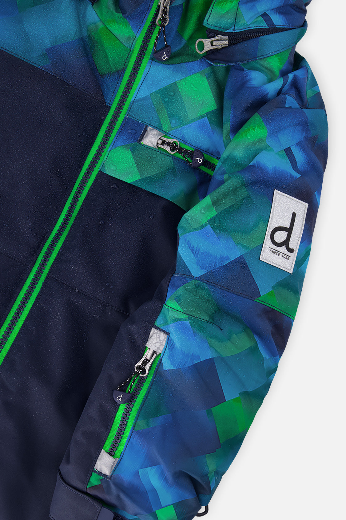 Close-up of the Deux par Deux blue and green checkered PLAY jacket zipper and sleeve logo patch