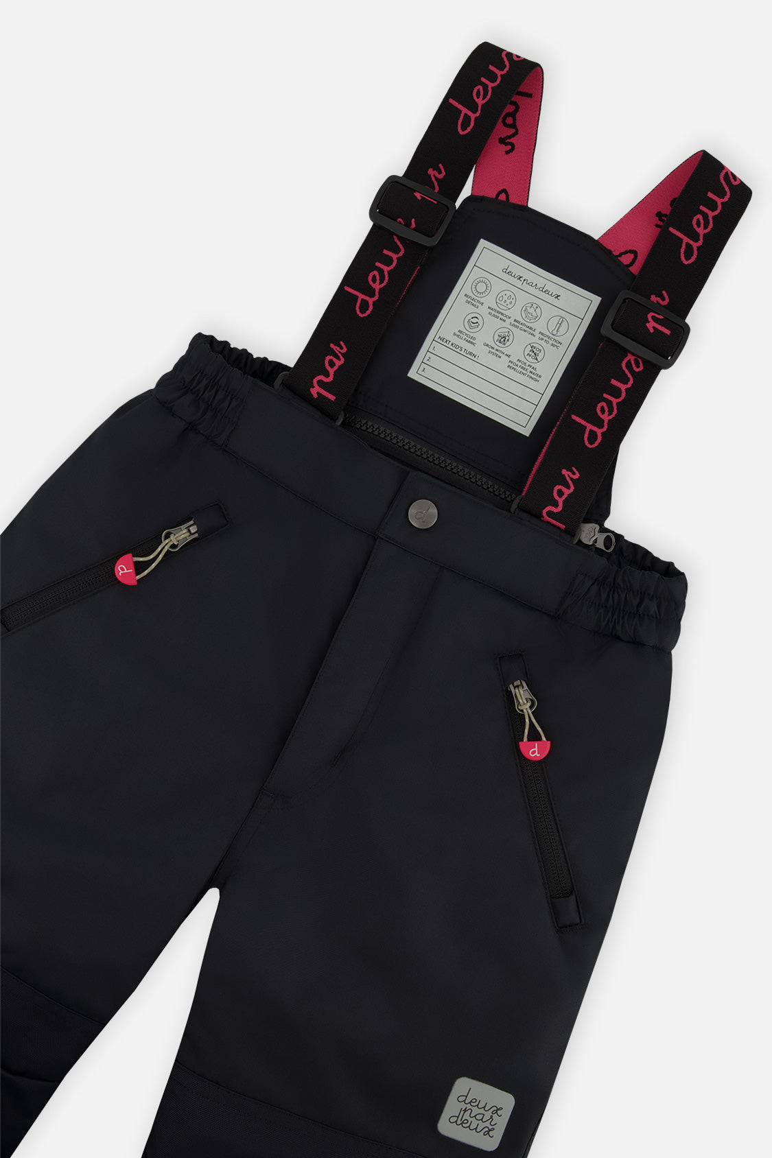 Deux par Deux girls PLAY snowsuit, coral, bright pink and black – close-up of the suspenders and zippered pant pockets