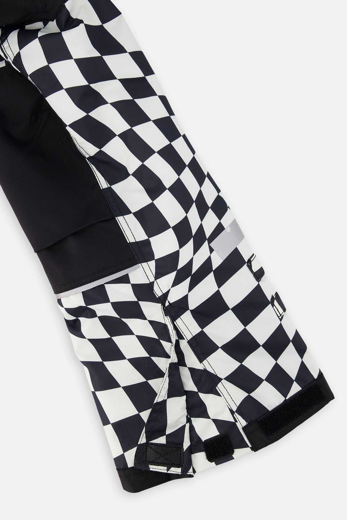 Close-up of the black and white checkered snow pants leg with reinforced panels and inner snow gaiter