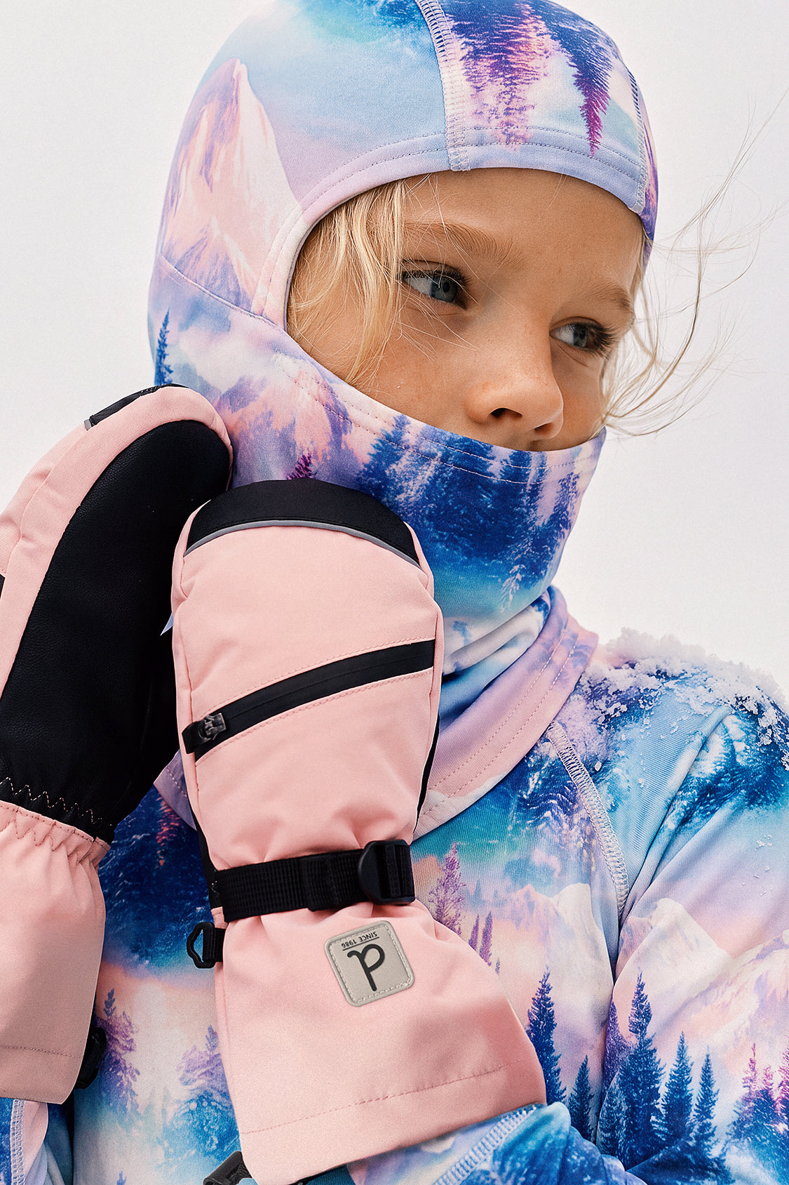 Deux par Deux girls' polar fleece balaclava in blue and pink mountain print – worn with winter mittens, lifestyle photo