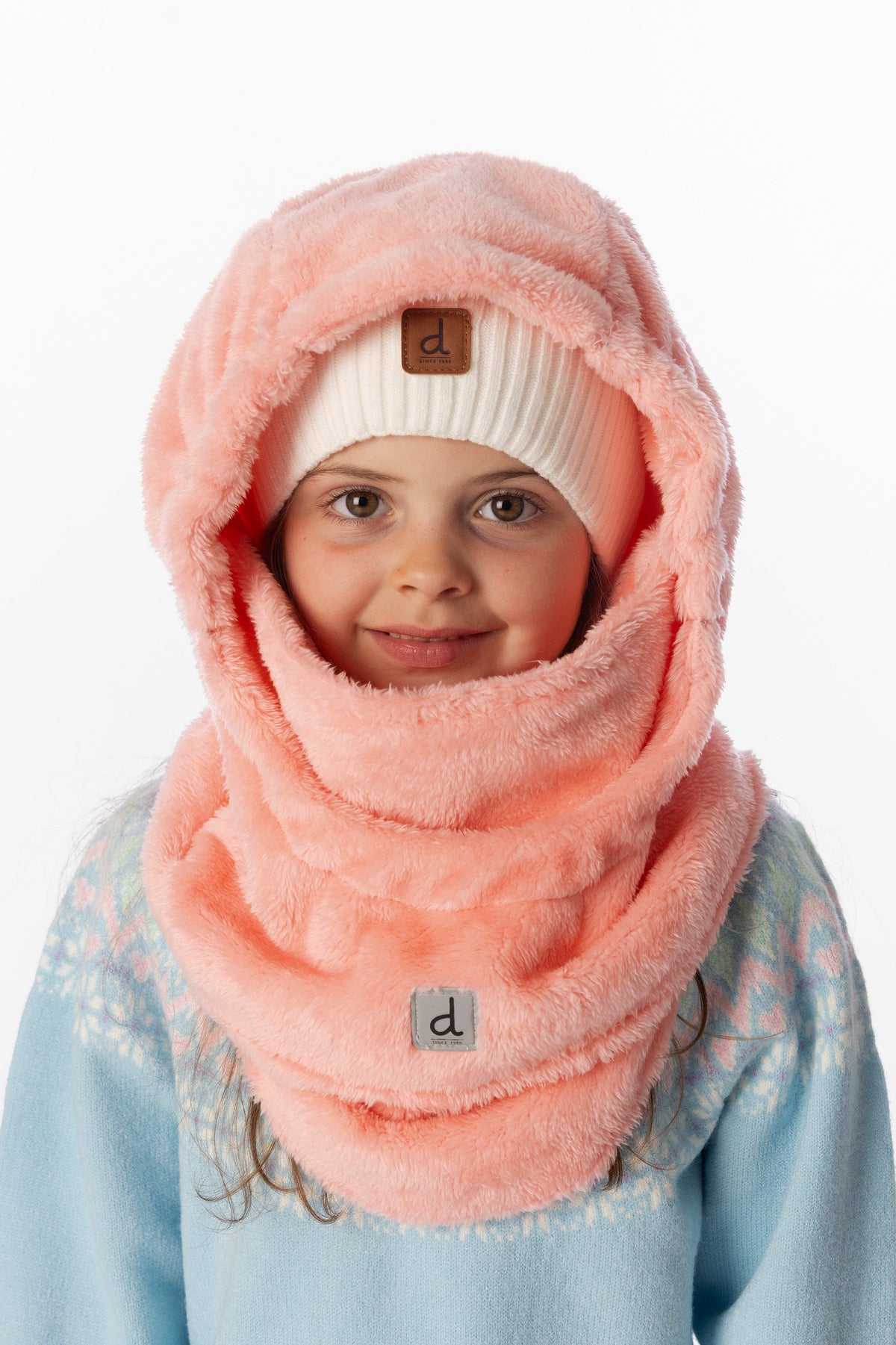 Child wearing the light pink Deux par Deux plush balaclava over a cream knit beanie
