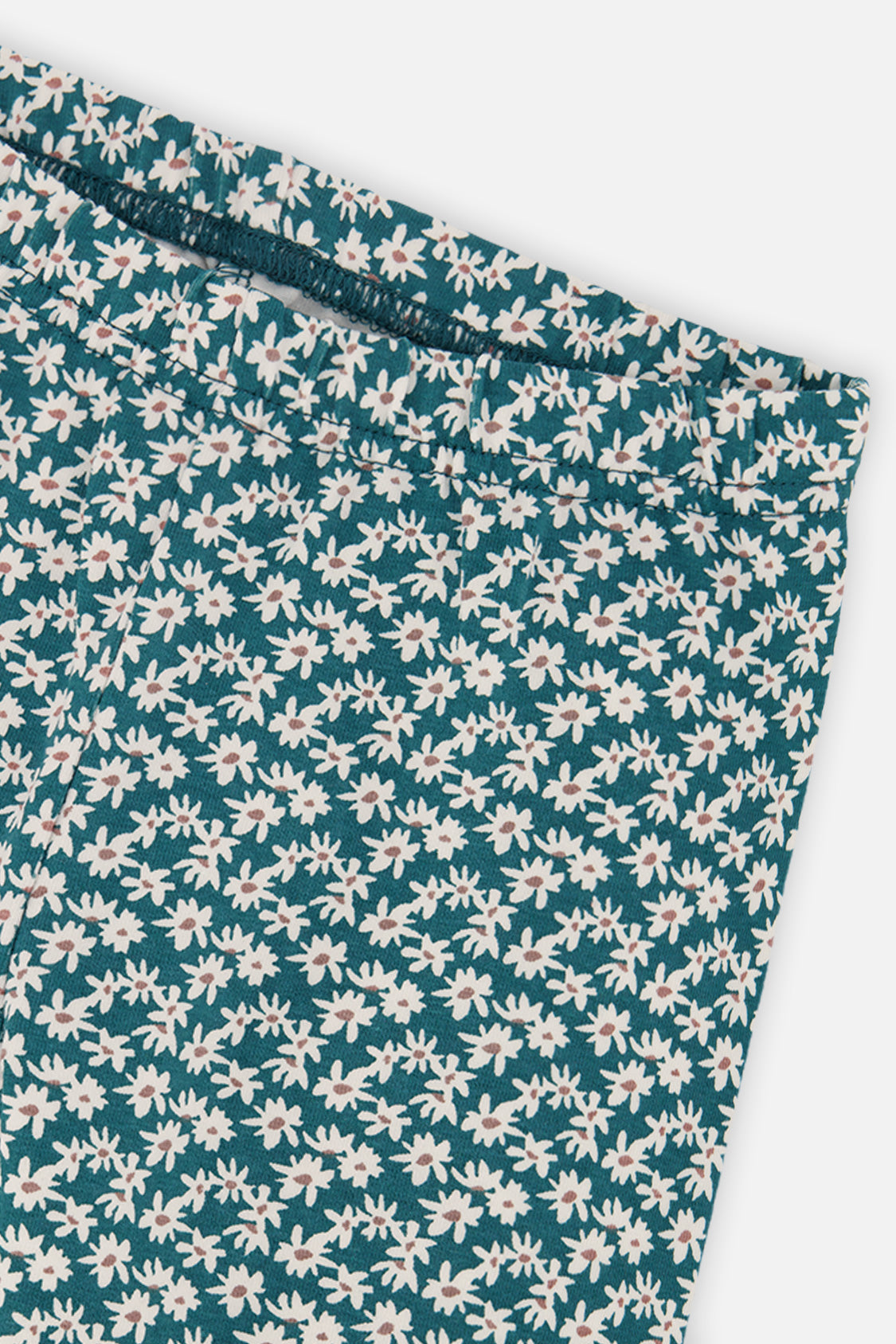 Close-up of the white daisy print and waistband on the Deux par Deux teal leggings