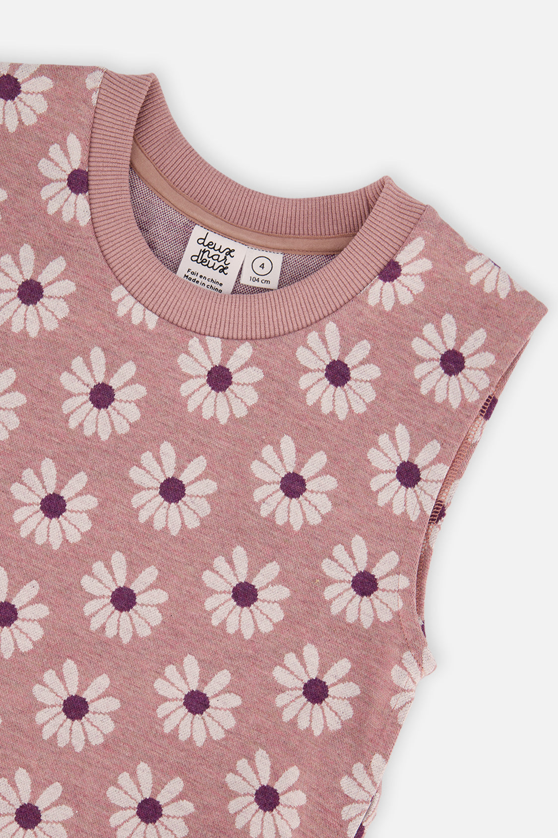 Close-up of the daisy jacquard pattern and ribbed crew neckline on the pink sleeveless vest