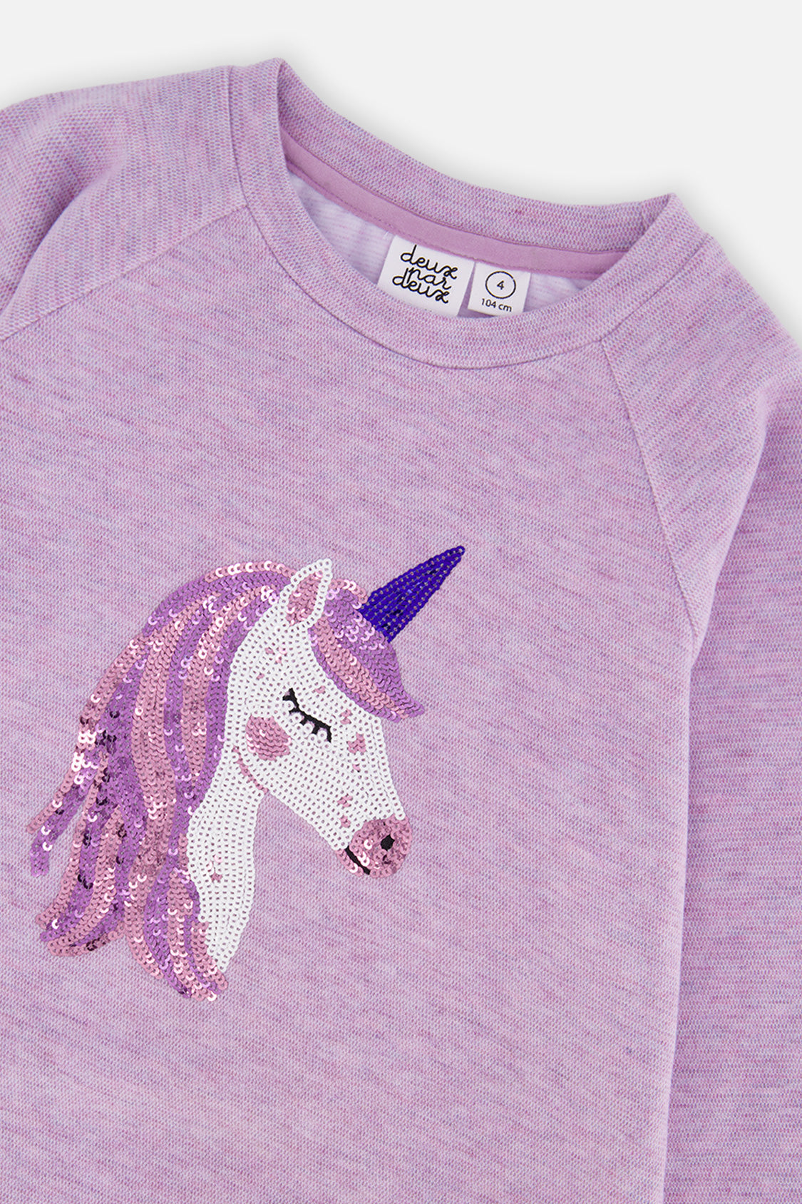 Close-up of the sequin unicorn and raglan sleeve on the violet tunic