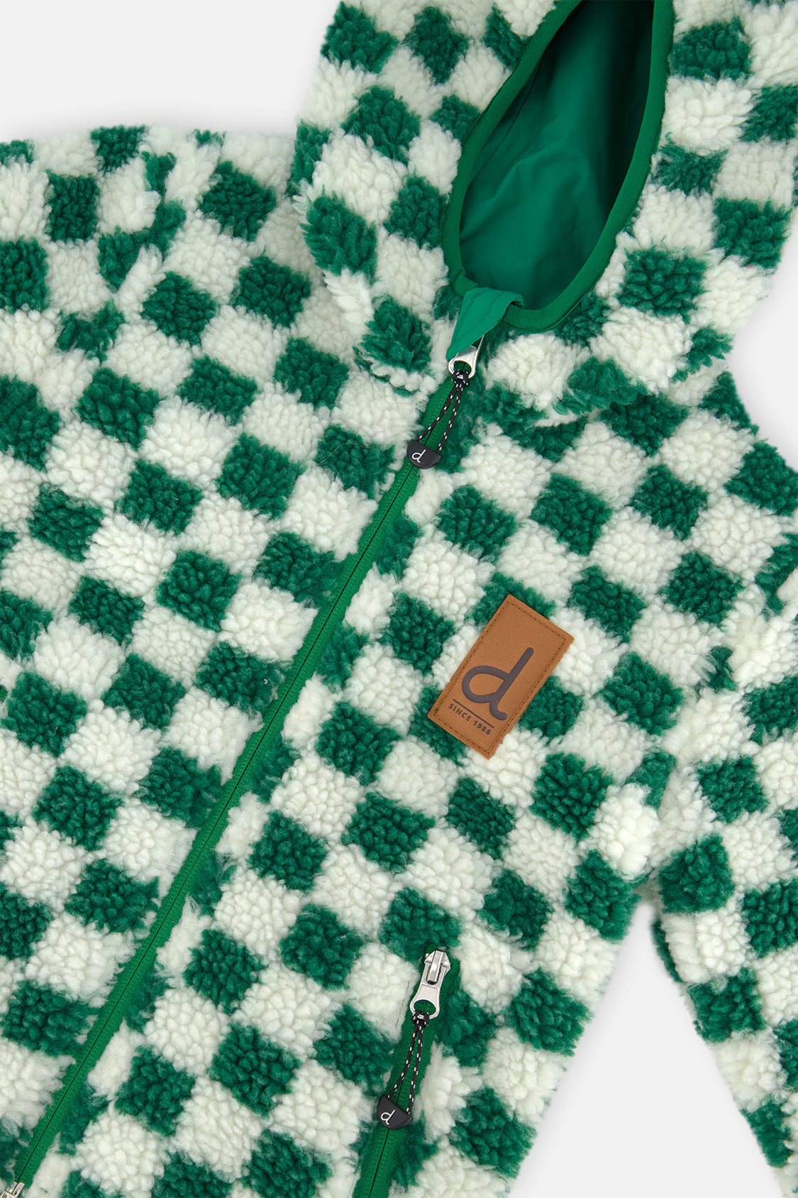 Close-up of the green and cream check sherpa, zipper and brand label