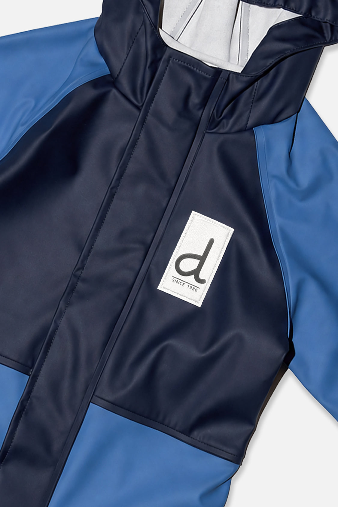 Close-up of the navy zipper placket and d logo patch on the blue rain one-piece