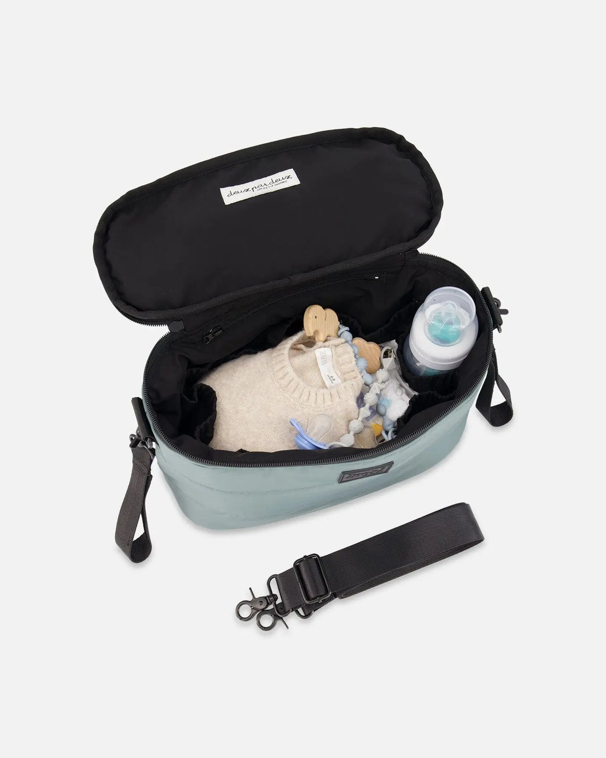 Open sage green diaper bag showing a bottle and baby clothes in the interior pockets