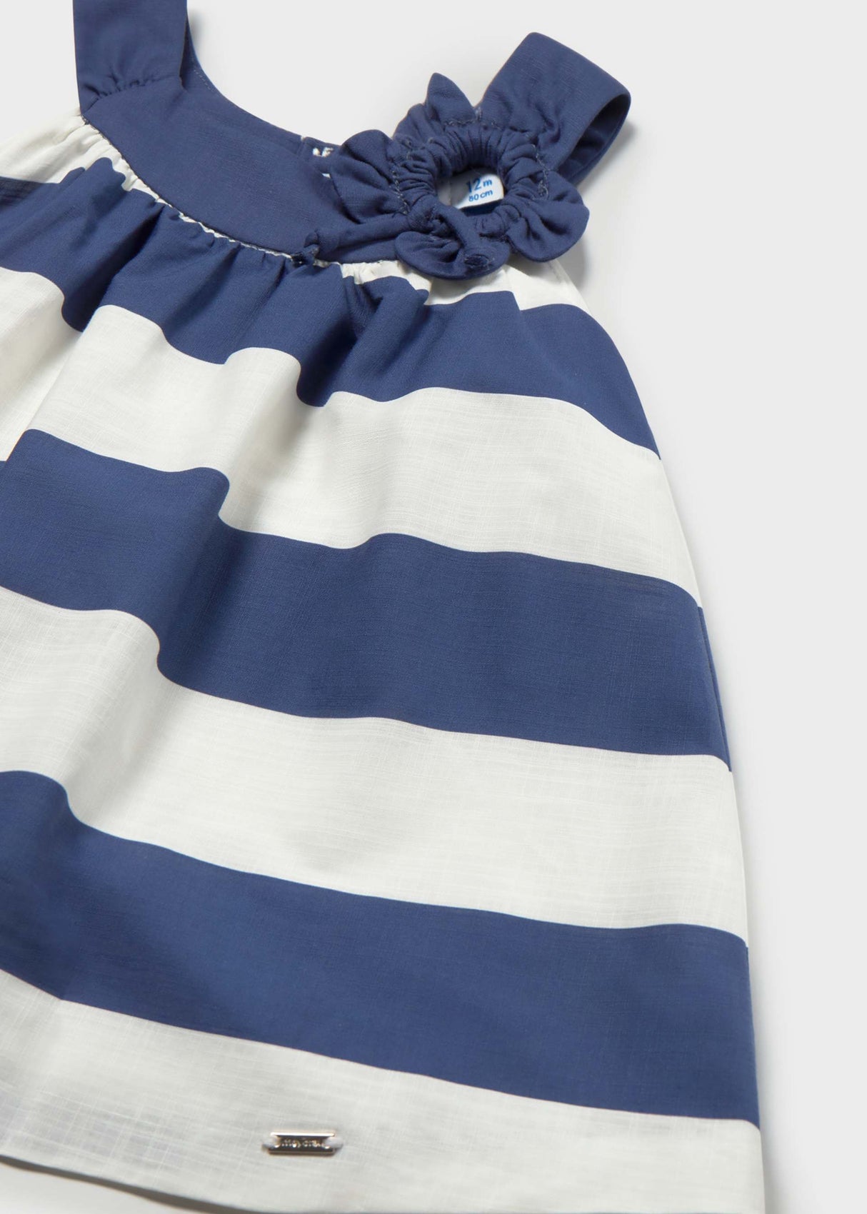 Closeup of Mayoral baby girl cotton dress showing Navy/White stripes and decorative flower detail.
