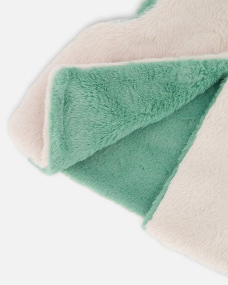 Corner of the vest folded back to show the sage green side against the off-white plush