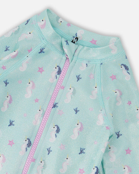 Close-up of the pink front zipper and seahorse print on the aqua rashguard one-piece