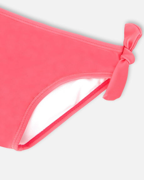 Close-up of the knotted side tie on the solid pink bikini bottom