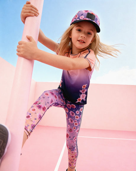 Child wearing the Deux par Deux floral gradient athletic leggings with a matching cap while climbing