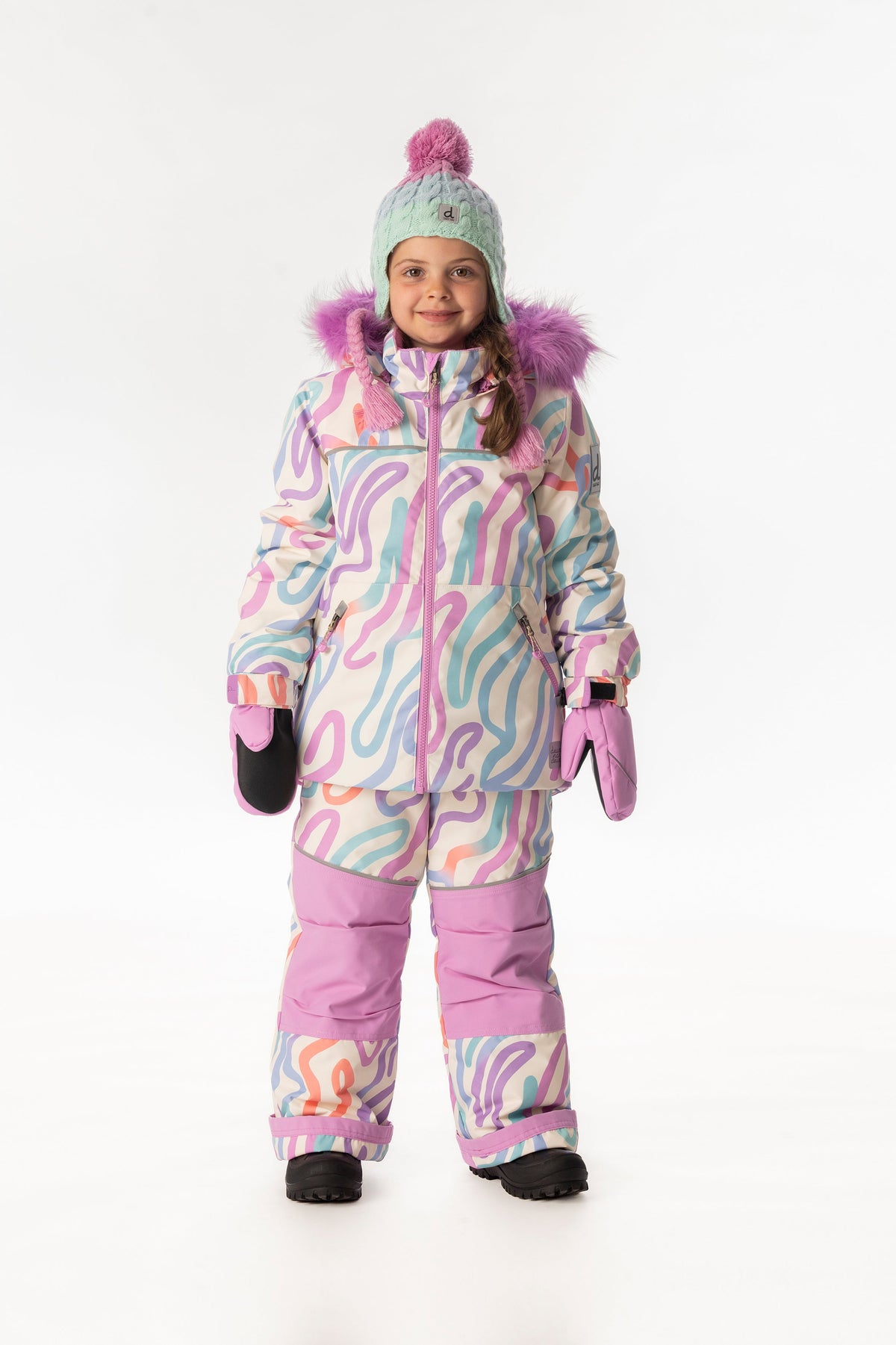 Girl wearing the multicolored line-print DISCOVER jacket with orchid knee-panel ski pants and a mint pom-pom hat, front view