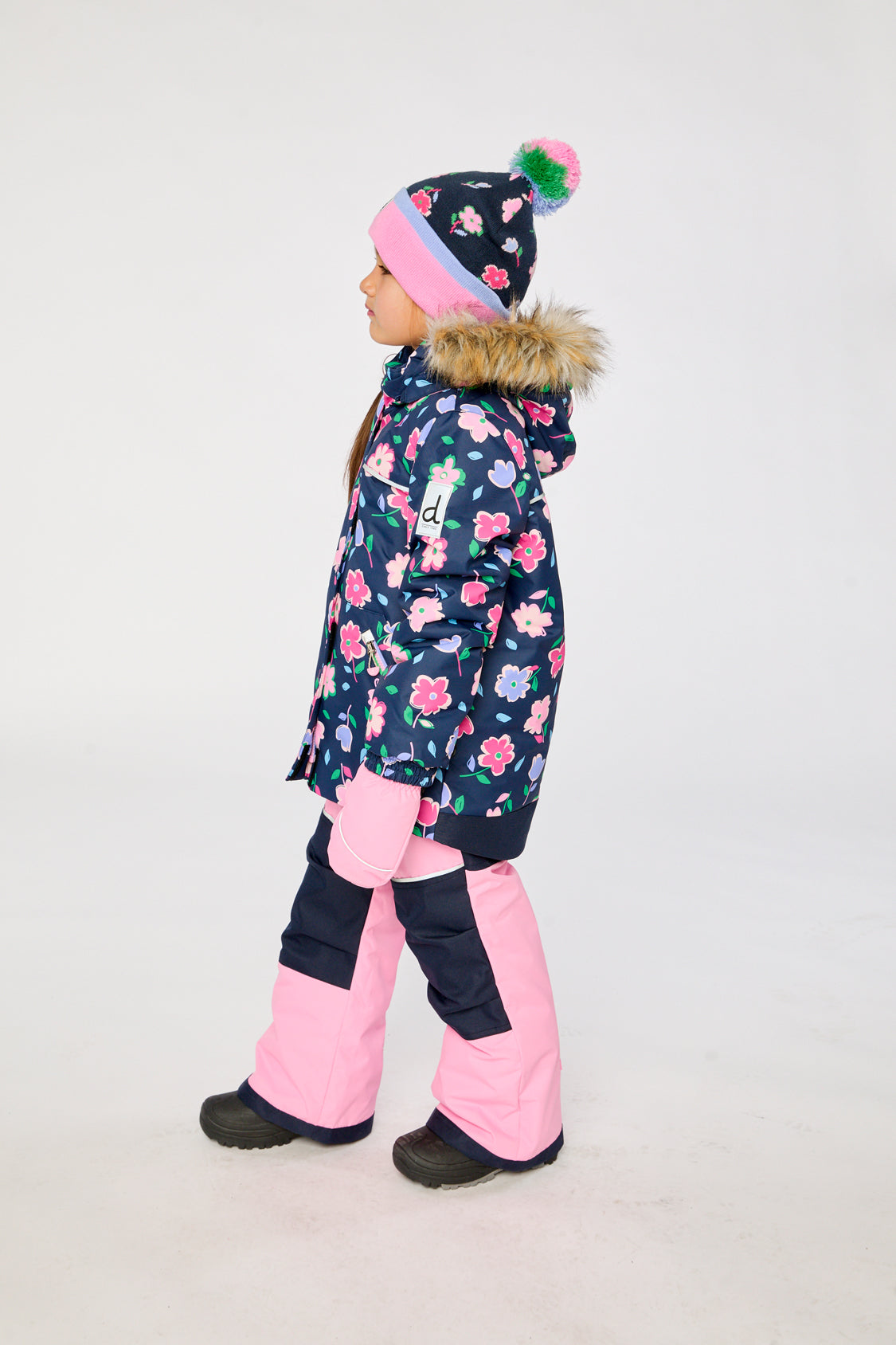 Child wearing the Deux par Deux navy floral DISCOVER snowsuit, side view