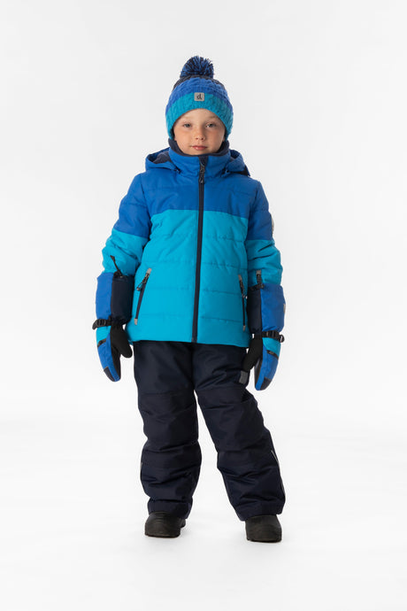 Boy standing in the light and dark blue Deux par Deux PLAY snowsuit, full-length front view