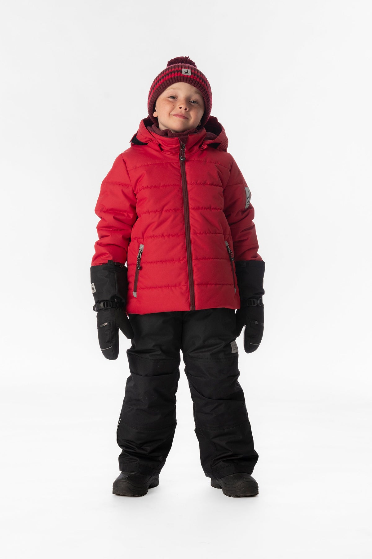 Boy standing in the red and black Deux par Deux PLAY snowsuit, full-length front view