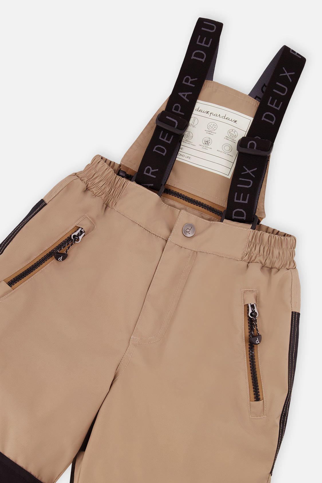 Close-up of the beige PLAY snow pants waist, zippered side pockets and suspenders