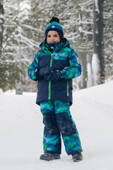 Child wearing the Deux par Deux blue and green checkered PLAY snowsuit on a snowy trail