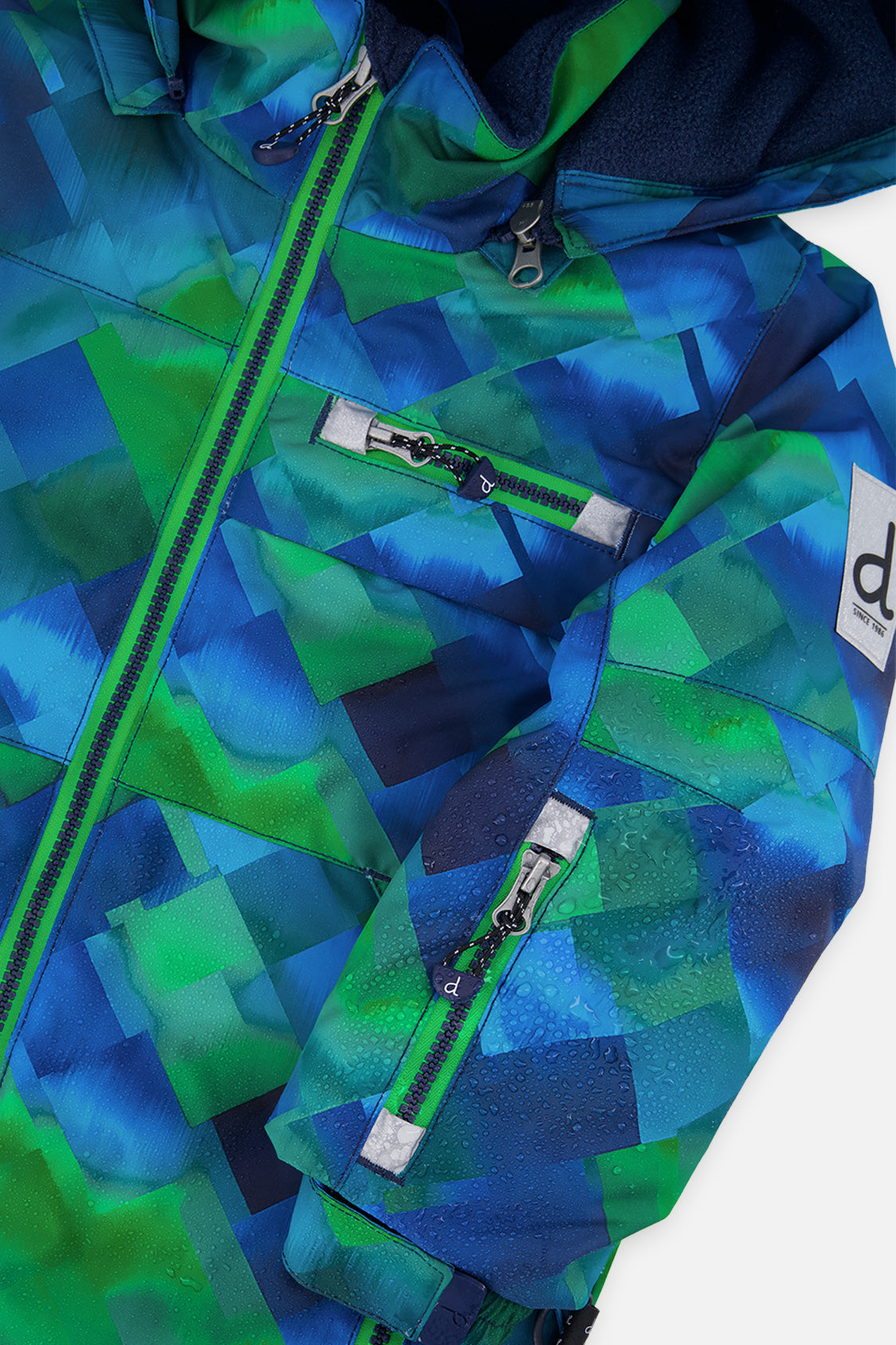 Close-up of the checkered PLAY jacket front zipper, chest pocket and sleeve logo patch