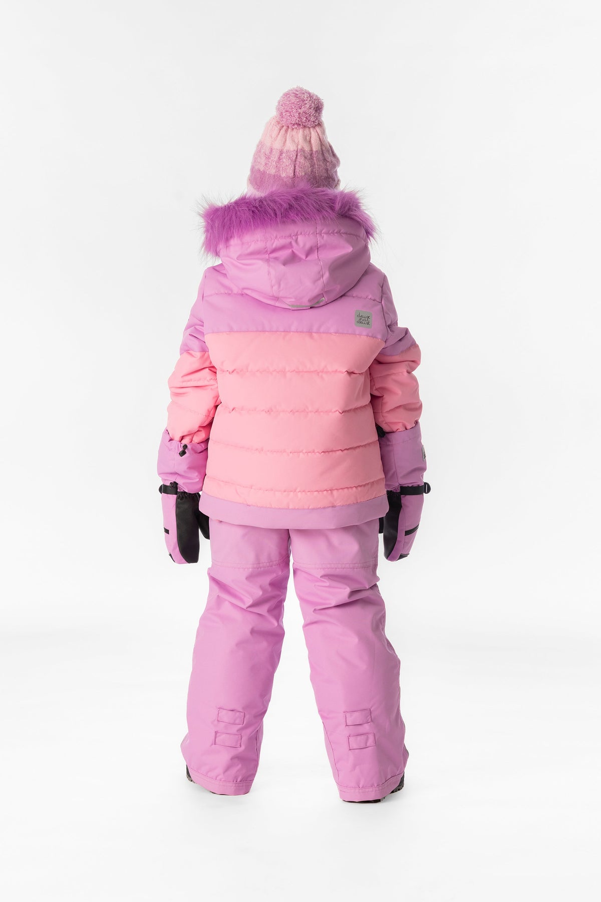 Girl in the pinkish violet and pink Deux par Deux PLAY snowsuit, back view