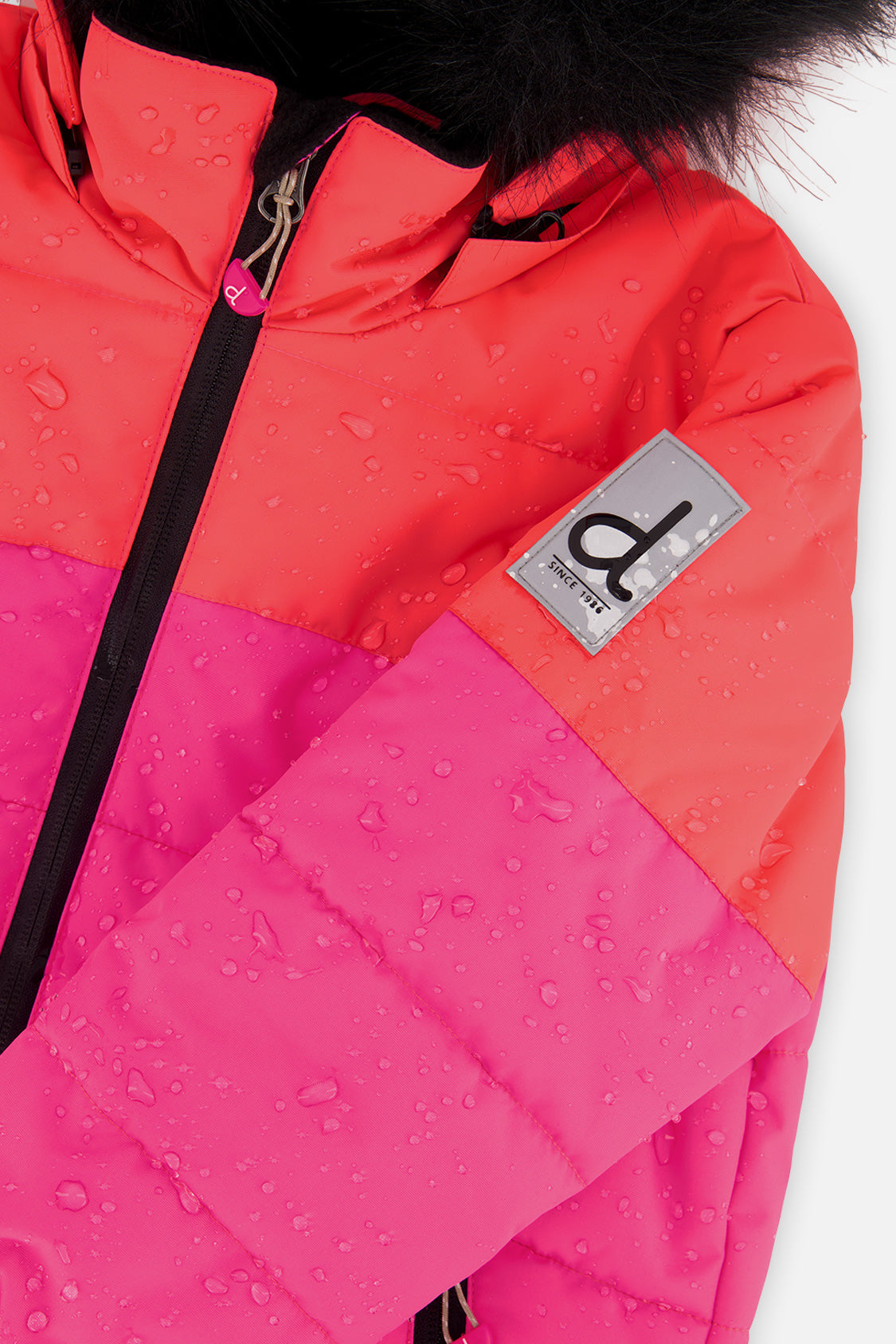 Deux par Deux girls PLAY snowsuit, coral, bright pink and black – close-up of the water-repellent jacket shell and logo patch