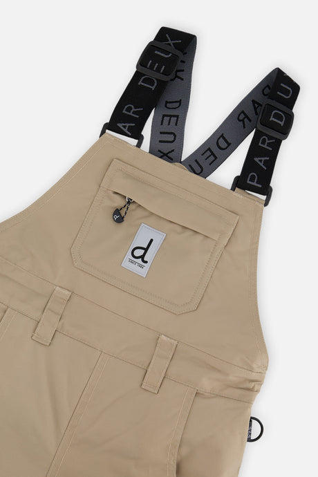 Close-up of the taupe PLAY bib chest pocket and logo suspenders