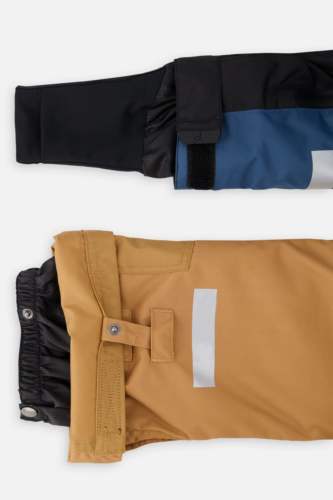 Close-up of the TEKNIK jacket cuff and the tan snow pant hem with snap tab