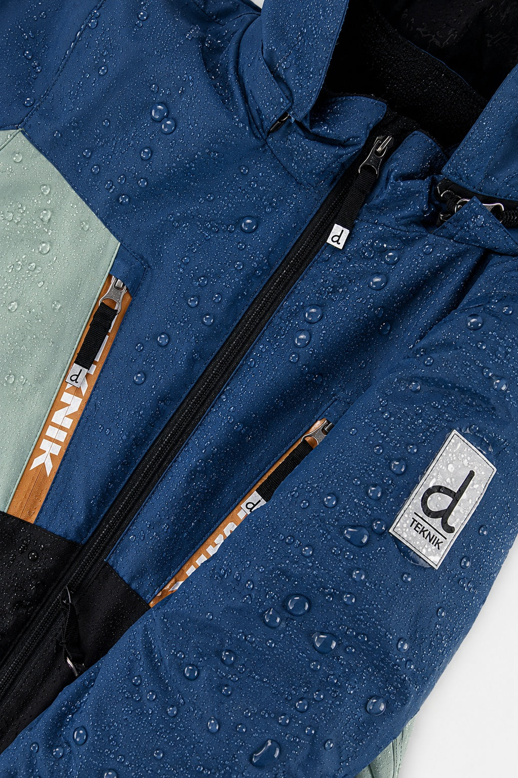 Water beading on the navy TEKNIK jacket beside the logo patch
