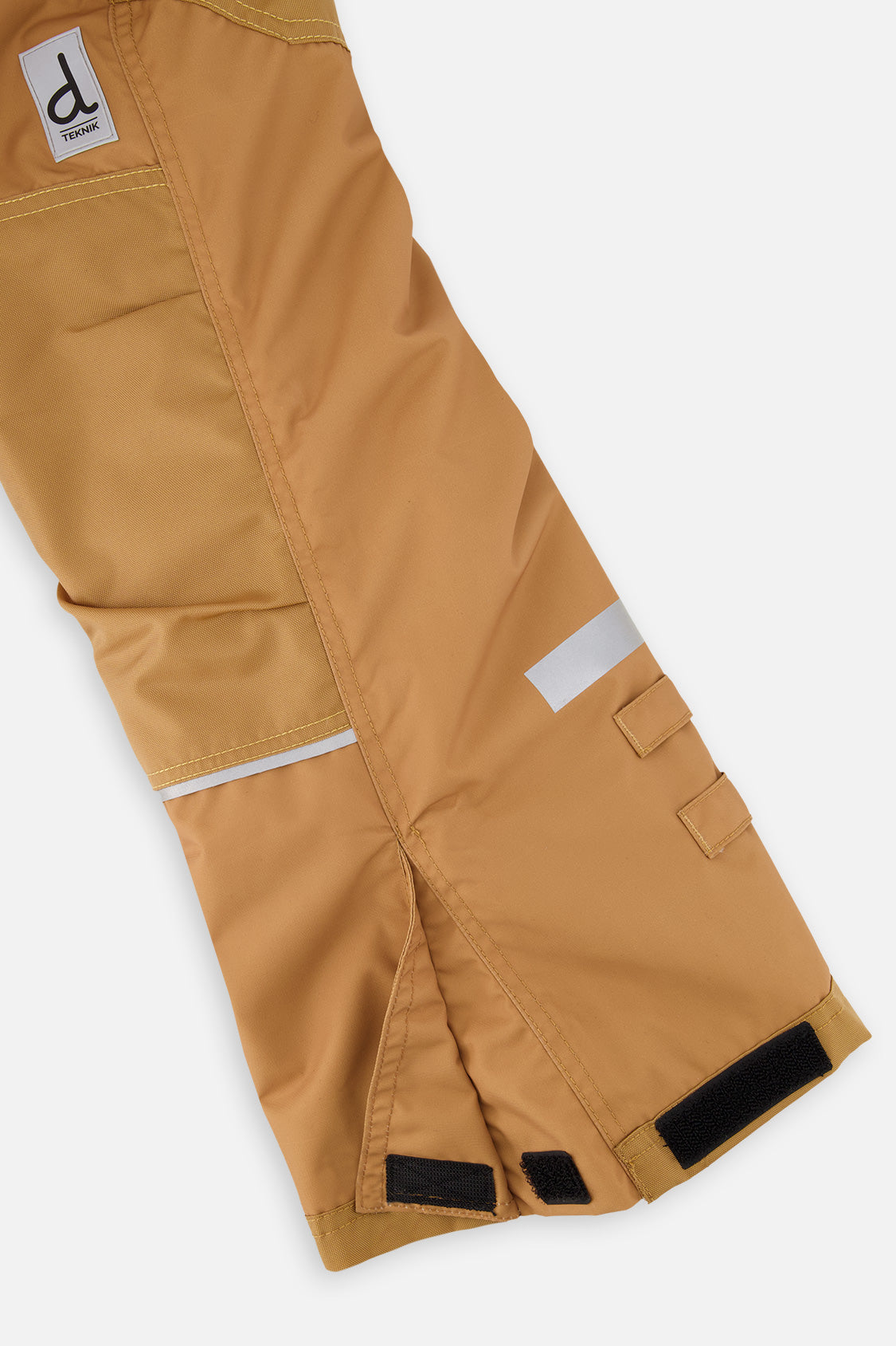 Close-up of the tan snow pants leg with reflective strip and reinforced panel