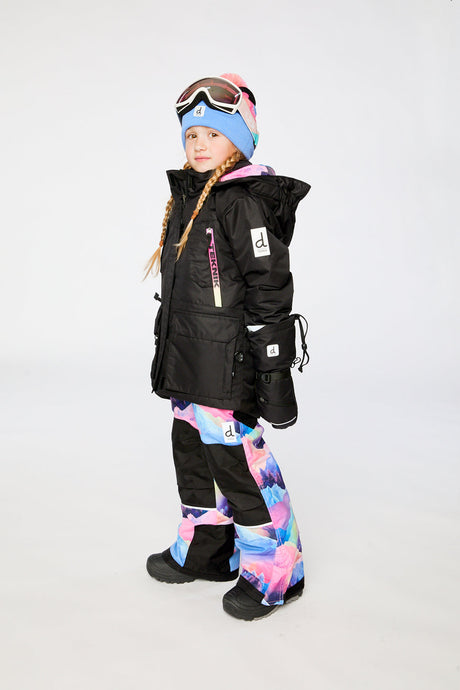 Deux par Deux girls' Teknik snowsuit, black jacket and pink-blue mountain print pants – on a child model, side view