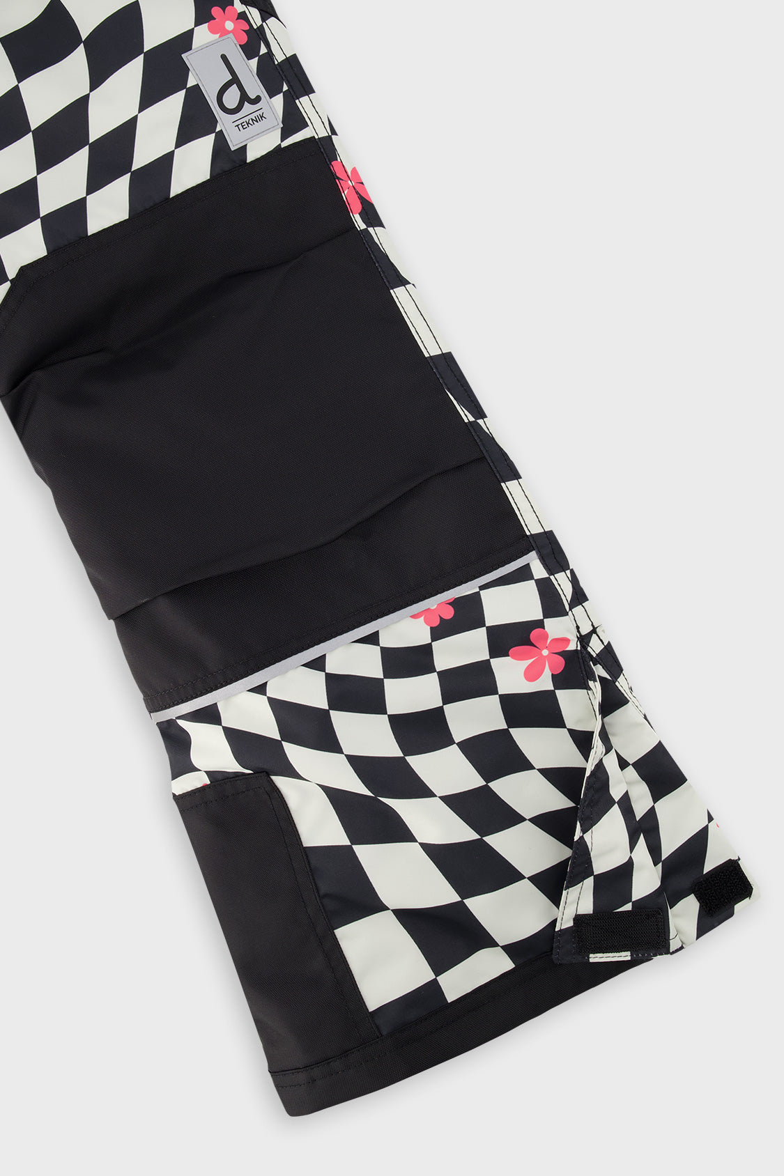 Close-up of the matching checkered snow pants leg with reinforced panels and inner snow gaiter