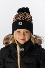 Smiling girl wearing the leopard print knit toque with a black cuff and a black puffer jacket, front view