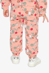 Back view of a child wearing coral pink French terry track pants with a cat print and white sneakers