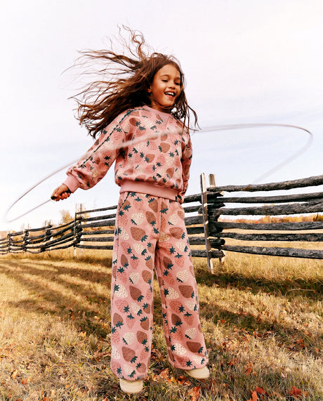 Child spinning a hula hoop outdoors in the strawberry print sweatshirt and matching pants