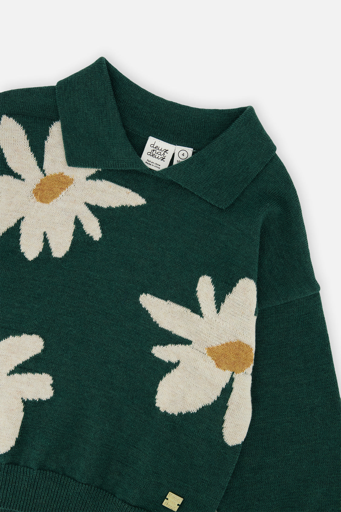 Close-up of the shirt collar and the cream daisy jacquard on the dark green Deux par Deux knit sweater