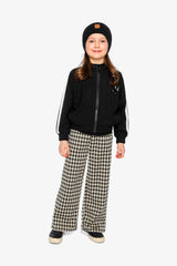 Girl in a black beanie, black jacket with white sleeve stripes and houndstooth flare pants, full-length view