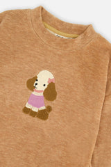 Close-up of the textured poodle appliqué and crew neckline on the brown velour tunic