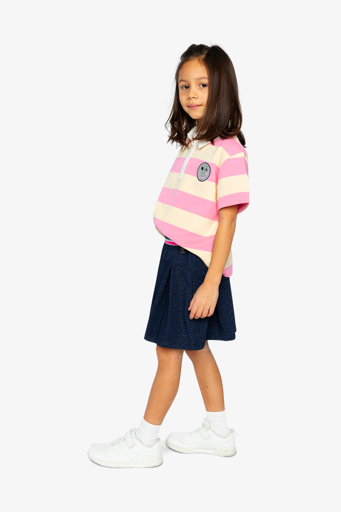 Child wearing the pink and beige striped polo shirt, full-length view