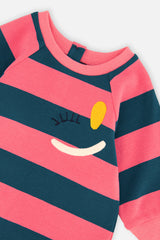 Close-up of the winking-face embroidery and ribbed crew neckline on the striped dress