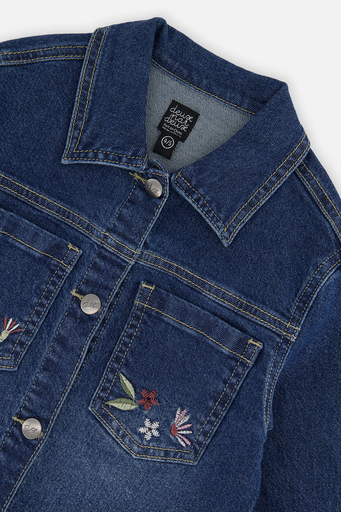 Close-up of the collar, button front and embroidered chest pocket on the blue denim jacket
