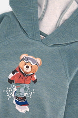 Close-up of the snowboarding teddy bear in goggles and the hood on the teal Deux par Deux hoodie