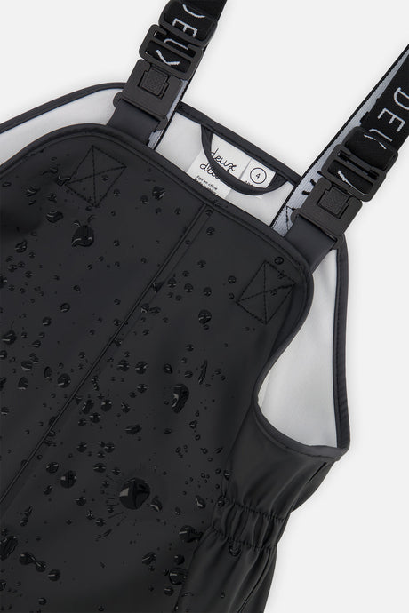 Water droplets beading on the black polyurethane bib of the Deux par Deux rain overalls