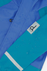 Close-up of the Deux par Deux label and reflective band on the dark turquoise rain jacket sleeve
