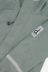 Close-up of the sage green rain jacket sleeve with the Deux par Deux label and reflective band