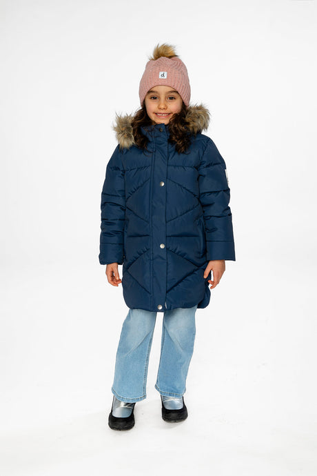Child wearing the long dark blue puffer coat snapped closed with a pink pom-pom hat and light jeans