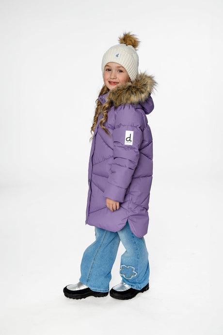 Side view of a child in the long violet coat with a cream pom-pom hat and light jeans