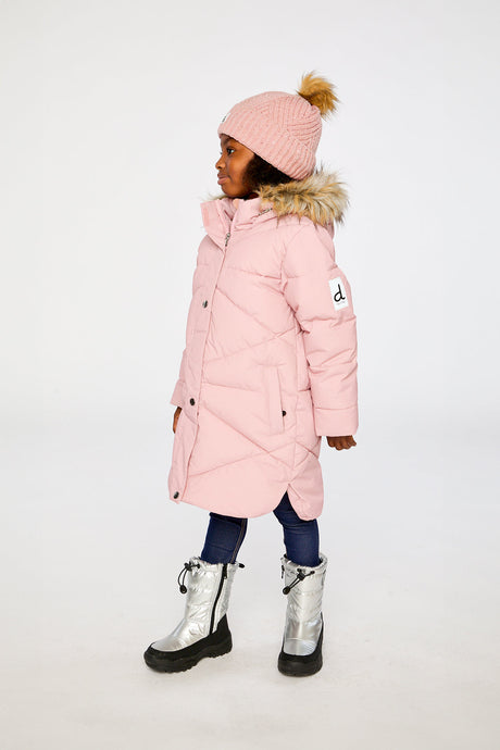 Side view of a girl in the long pale dusty pink puffer coat and silver snow boots